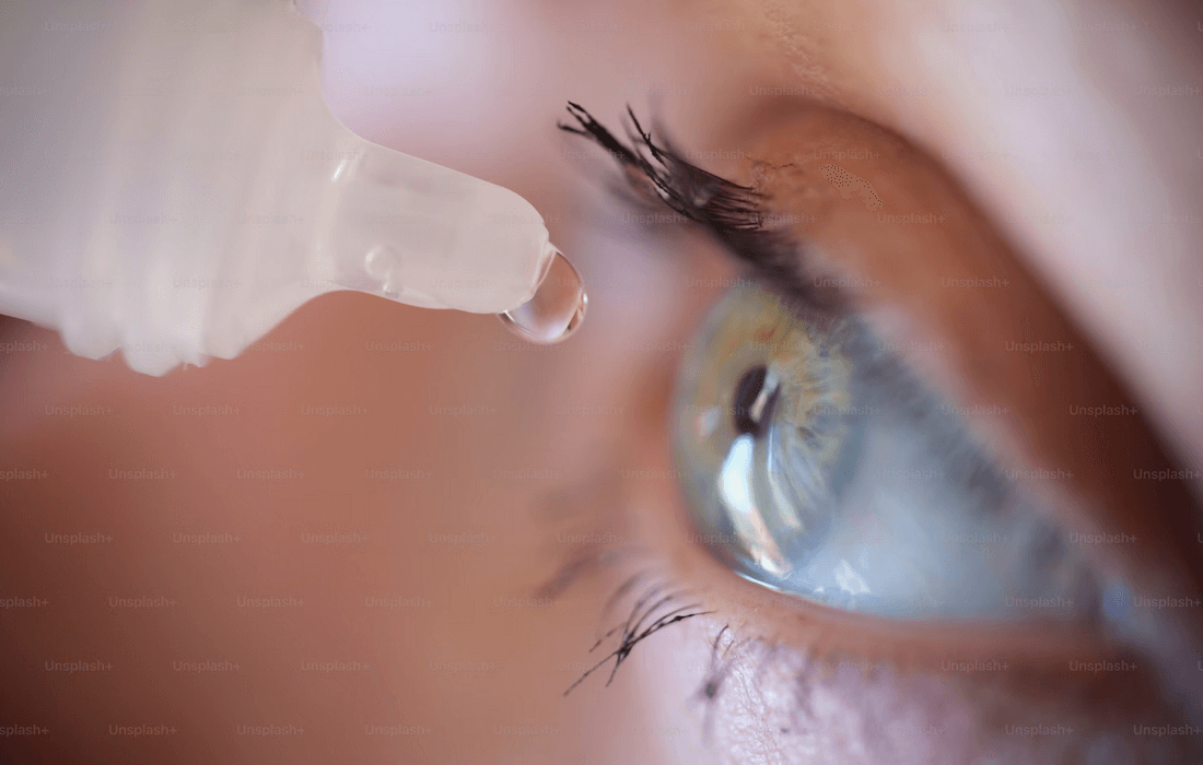 A person using eye drop medication